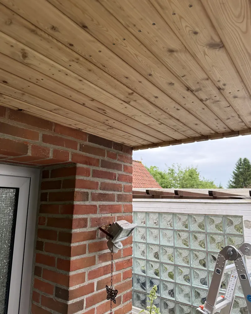Untersicht eines Vordachs mit heller Holzschalung über Klinkermauerwerk