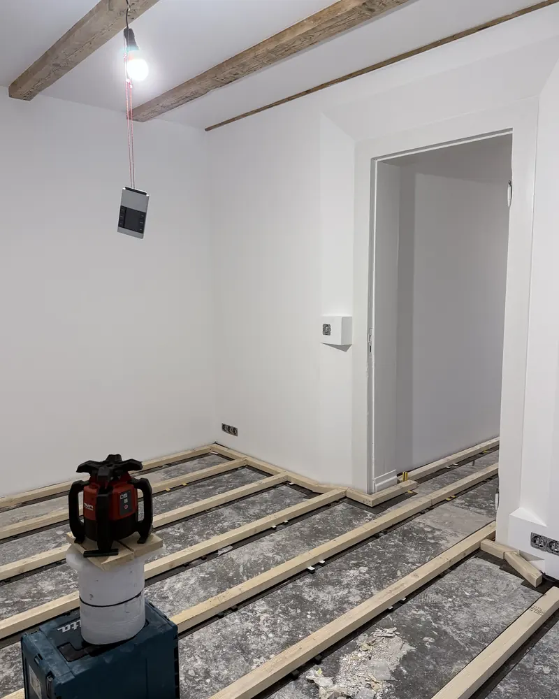 Sanierter Raum mit sichtbarer Balkendecke und neuen Lagerhölzern für den Fußboden