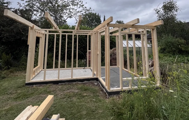 Holzständerrohbau eines Gartenhauses im Garten